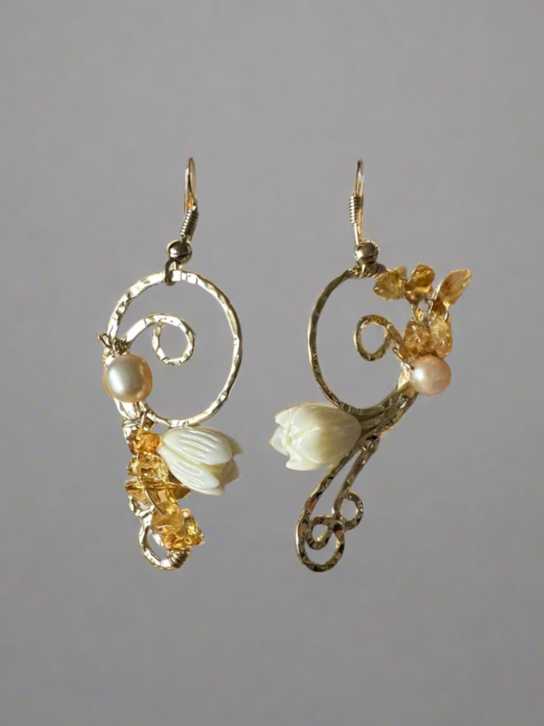 Pair of earrings with floral and pearl details on a textured surface