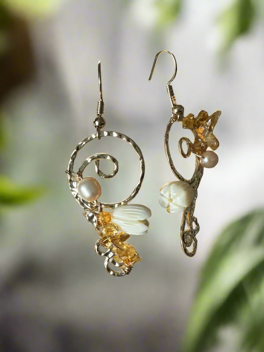 Pair of earrings with floral and pearl details on a textured surface