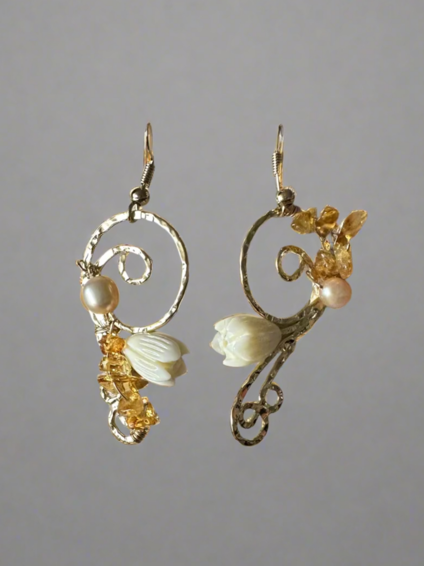 Pair of earrings with floral and pearl details on a textured surface
