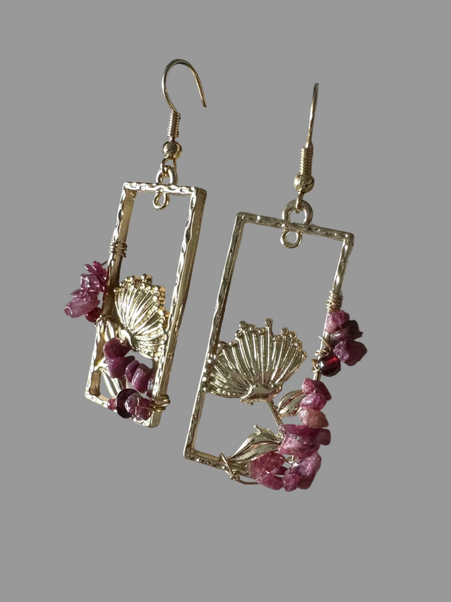 Gold earrings with pink stones on a textured surface