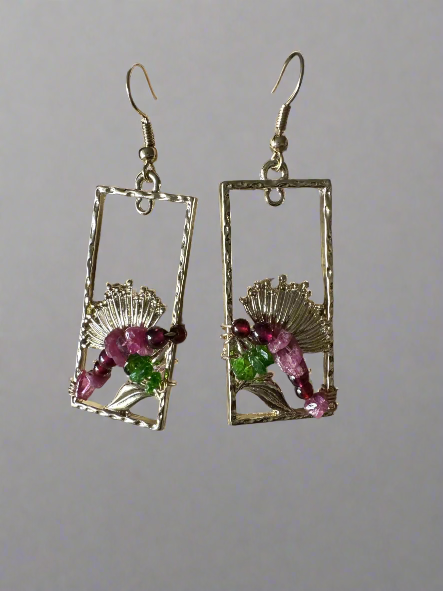 Gold-framed earrings with gemstones on a textured surface
