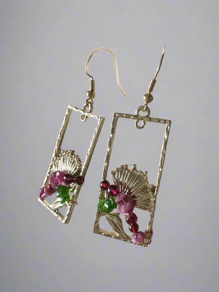 Gold earrings with gemstones on a textured surface