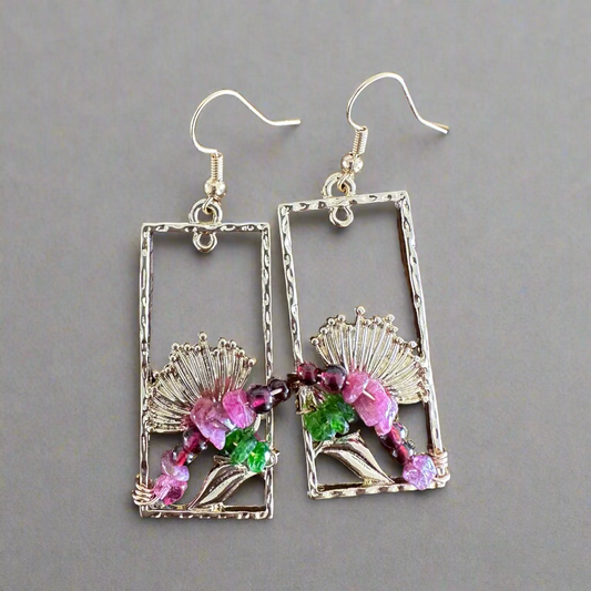 Pair of Hamilton gold earrings with floral designs on a wooden surface