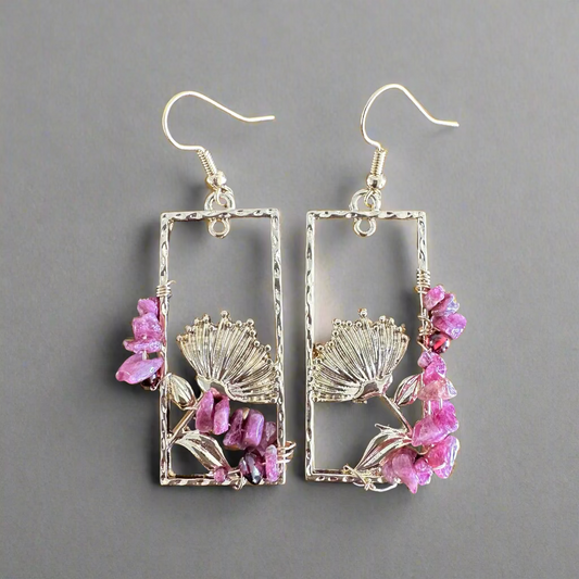Gold colored earrings with pink stones on a wooden surface